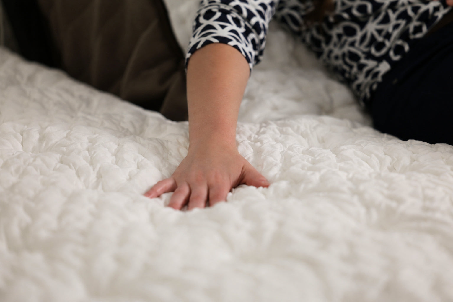 A hand pressing into the quilted surface of a Bread Rest mattress